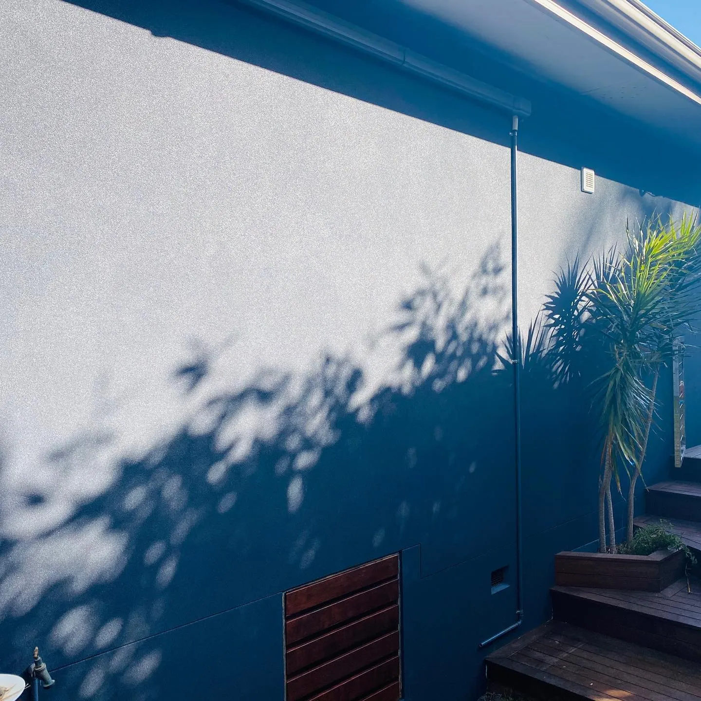 Rendered courtyard wall beside a timber deck and pool area